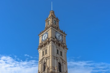 The clock tower of the Melbourne GPO building against a blue sky with light cloud cover