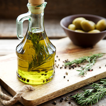 Flavored olive oil with rosemary and pepper on wooden background