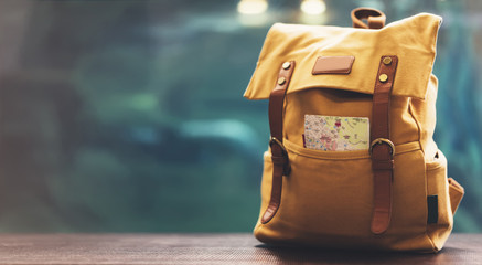 Hipster yellow backpack and map closeup. View from front tourist traveler bag on background blue...