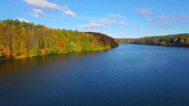 Autumn nature aerial landscape flight over forest lake and brightly colored trees.