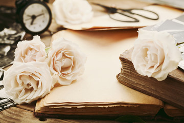 Retro still life with vintage rose flowers and open ancient book. Nostalgic composition on old...