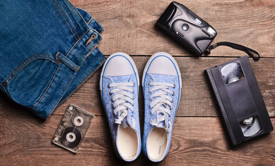 Back in the 90s. Shoes, audio tapes, video tapes, jeans, camera.Top view. Flat lat.