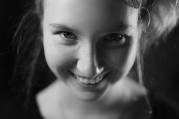 closeup portrait of teenage girl smiling in dark studio, shallow focus