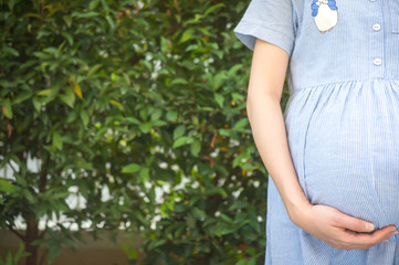 Close up of pregnant woman are relaxing in the garden at house. pregnant woman holding her belly in the garden