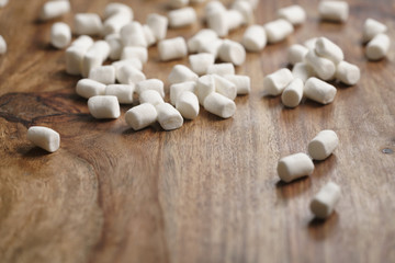 Fototapeta na wymiar falling white marshmallows on wooden table, slight motion blur