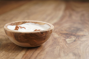 homemade yogurt with hazelnuts in wood bowl on wooden table, shallow focus