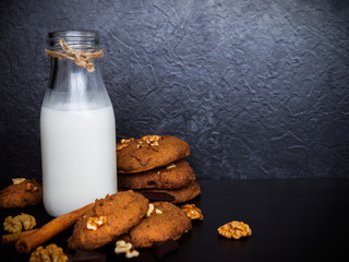 A glass of milk and healthy cookies on dark background