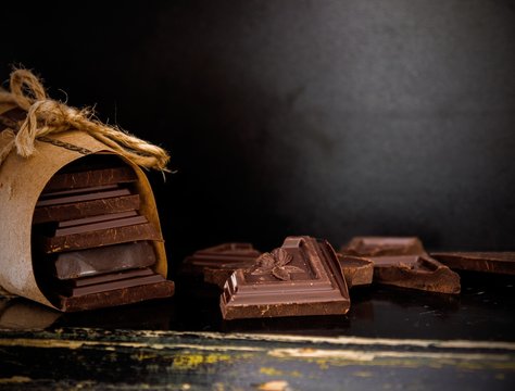 broken bar of dark chocolate isolated on dark background