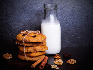 A glass of milk and healthy cookies on dark background
