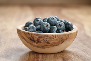 fresh blueberries in wood bowl on table, shallow focus