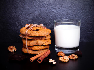 A glass of milk and healthy cookies on dark background
