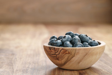 fresh blueberries in wood bowl on table with copy space, shallow focus