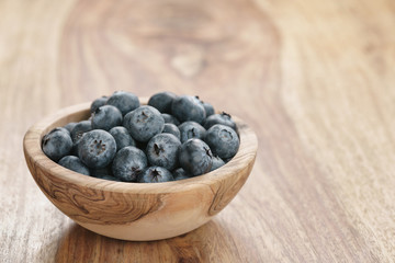 fresh blueberries in wood bowl on table with copy space, shallow focus