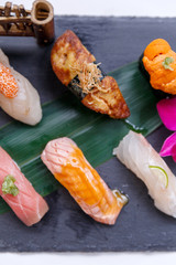 Premium Sushi Set Include Engawa, Hamachi, Hotate, Toro, Foie Gras, Salmon, Sea Urchin and Tai Served with Wasabi and Prickled Ginger on The Black Stone Plate.
