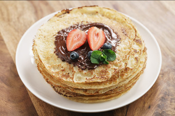 fresh blinis or crepes with melted dark chocolate and berries, shallow focus
