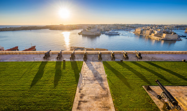 Valletta, Malta - Beautiful sunrise at the famous saluting battery of Valletta with Grand Harbor and Senglea and Brigu at background. Blue sky and sunlight.