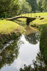 Fototapeta na wymiar Petit pont sur un ruisseau à Marche-en-Famenne Belgique, Magnifique reflet sur l'eau des arbres avoisinants.