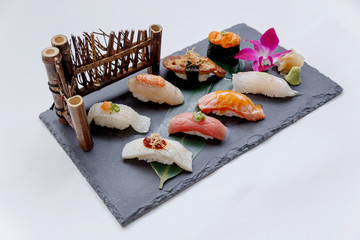 Premium Sushi Set Include Engawa, Hamachi, Hotate, Toro, Foie Gras, Salmon, Sea Urchin and Tai Served with Wasabi and Prickled Ginger on The Black Stone Plate.