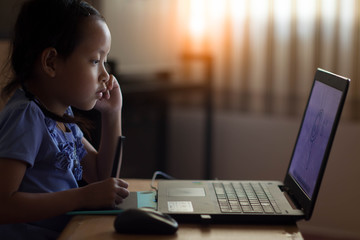 Cute child drawing by pen and laptop at home.Low key and Selecti