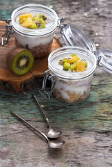 Breakfast yogurt with oatmeal and orange Kiwi fruit on a wooden background top view