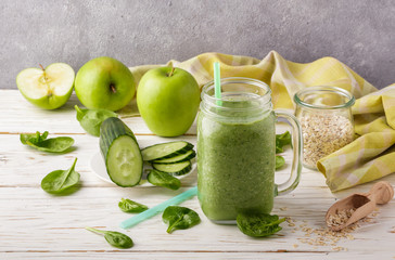 Fresh green smoothie from fruit and vegetables for a healthy lifestyle and ingredients for making dietary drink (spinach, green Apple, cucumber, oatmeal)

