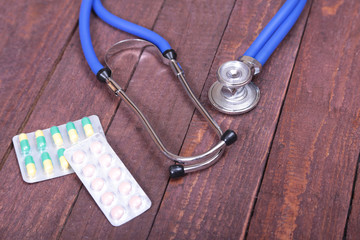 Stethoscope and tablets isolated on wooden background