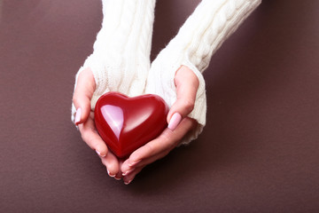 Female hands giving red heart, isolated on brown background