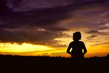 Fototapeta na wymiar woman silhouette standing in front of a sun setting sky