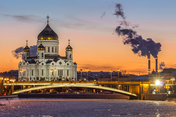 Fototapeta na wymiar Cathedral of Christ The Savior and Moscow river at frosty winter sunset. Smoke of power plants.