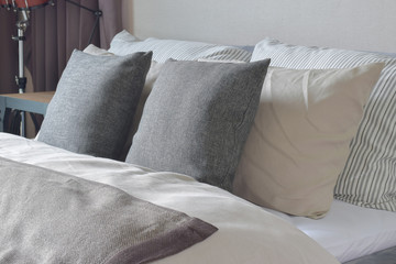 Dark gray and white pillows setting on bed with comfy blanket