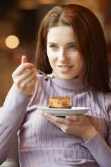 Portrait of young pretty smiling woman eating cake at shopping m