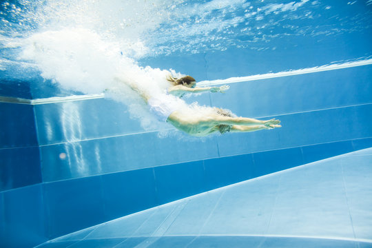 Underwater View Of A Young Couple Jumping Into The Water