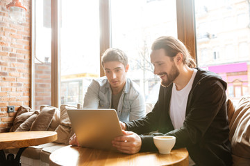 Side view of Friends with laptop in cafe