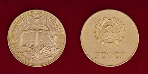 Gold school medal of USSR on red background. Text translation: "For excellent achievements in the teaching of"