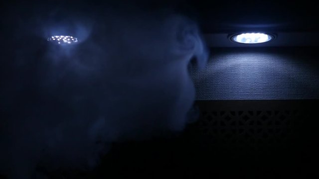 thick clouds of smoke from the hookah breathe in the dark blue light bulbs, slow motion, HD