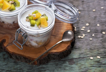 Breakfast yogurt with oatmeal and orange Kiwi fruit on a wooden background top view