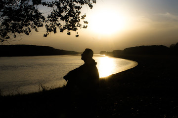 Picture of a young man meditating alone on a river shore