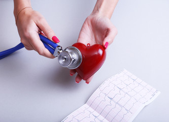 Female medicine doctor hold in hands red toy heart and stethoscope head. Cardio therapeutist, student education, physician make cardiac physical, rate measure, arrhythmia concept