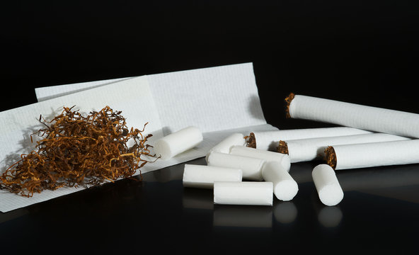 Homemade cigarettes, tobacco,  filters and tobacco paper on blac
