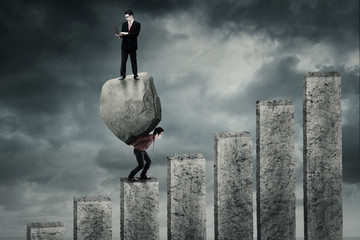 Worker climbing chart with boulder and partner © Creativa Images