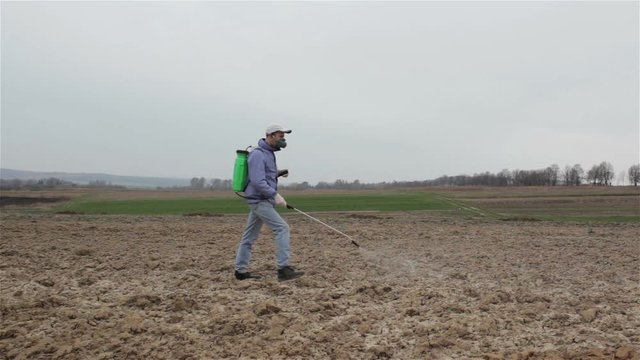 spring spraying herbicides/Man sprays herbicides in spring field
