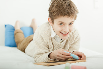 Smiling happy young boy drawing on a slate © Jan H. Andersen