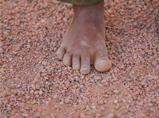 dirty children's foot is in the desert sand