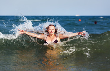 Close-up portrait of a beautiful young woman against the sea with the waves and the cloudless sky on a sunny day.