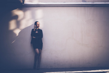 Business women standing side wall in evening with light and shadow.