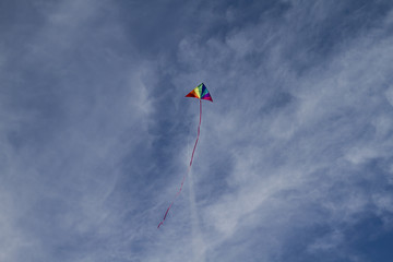 Fototapeta na wymiar Recreational, Kite of rainbow colors on a blue sky with light wh