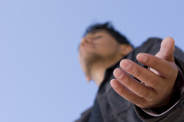 Hispanic man with open arm in prayer.