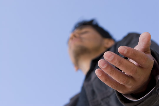 Hispanic Man With Open Arm In Prayer.