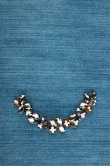 Fashionable background, jewelry with rhinestones lying on denim.