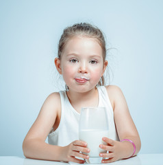 beautiful cute little girl drinking milk and licking lips